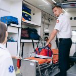 Dois paramédicos organizam suprimentos médicos dentro de uma ambulância para atendimento de emergência.