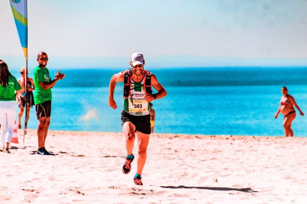Corredor participa de uma prova na faixa de areia à beira-mar em um dia ensolarado