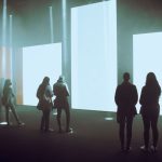 Visitantes exploram uma instalação de arte digital imersiva com grandes telas iluminadas.