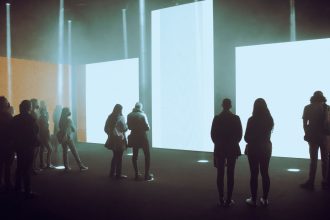 Visitantes exploram uma instalação de arte digital imersiva com grandes telas iluminadas.