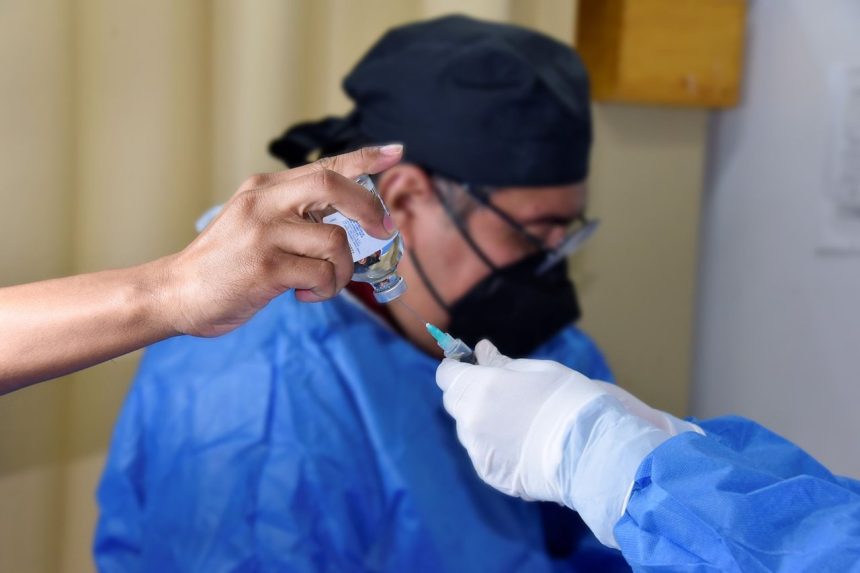 Profissional de saúde prepara uma seringa para vacinação em ambiente interno.