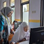 Professora orienta estudante durante atividade em um computador em um laboratório de informática.