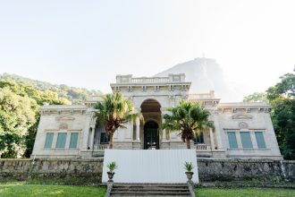 Casarão histórico cercado por vegetação tropical no Rio de Janeiro.