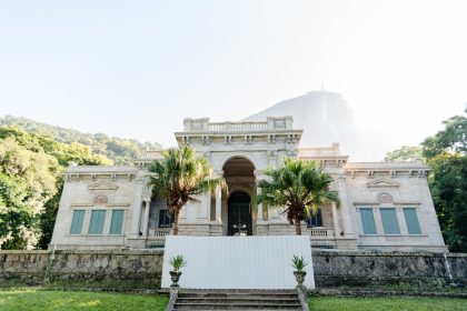Casarão histórico cercado por vegetação tropical no Rio de Janeiro.